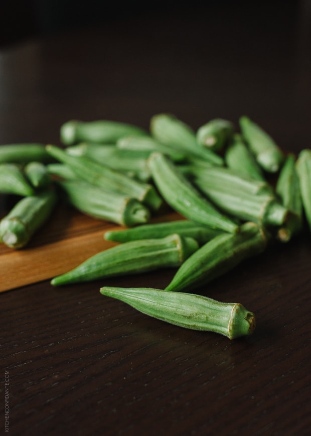 Fresh green okra on a wooden surface.