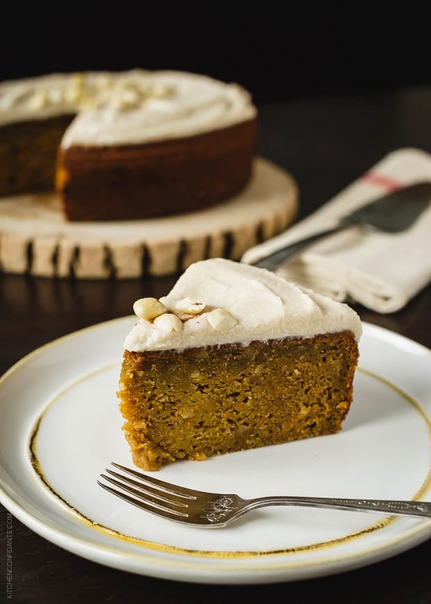 A slice of frosted pumpkin cake on a white plate.