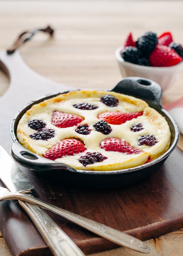 A Dutch Baby Pancake in cast iron pan with strawberries and blackberries baked into the top.