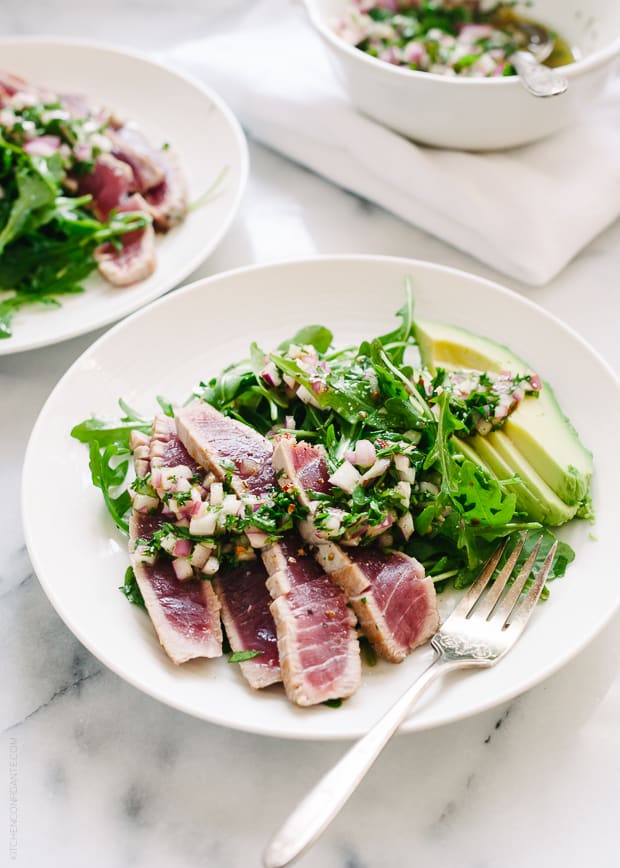 Seared Ahi Tuna with Chimichurri Sauce, Arugula and Avocado on a white plate.