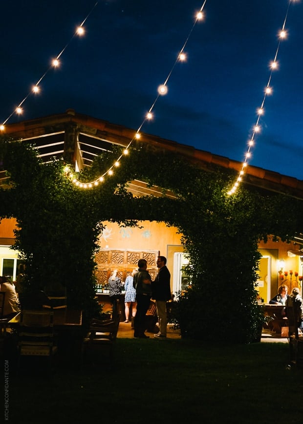 A nighttime view of the event venue, with ivy growing up the structure, and illuminated with swag lighting.