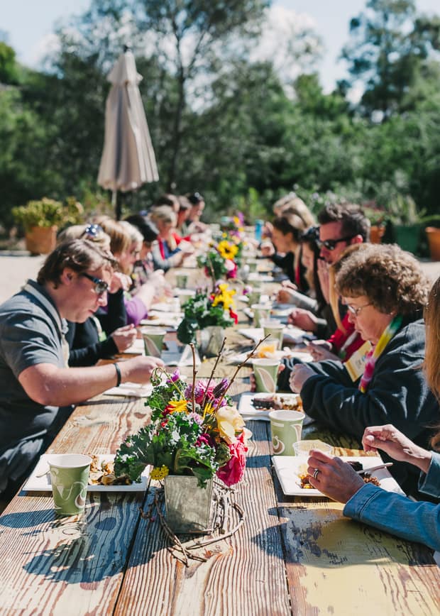 An image of the attendees eating food along long picnic tables outside.