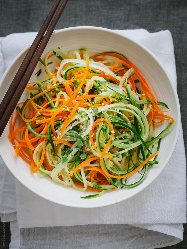 Asian Cucumber Carrot Slaw in a white bowl garnished with sesame seeds.