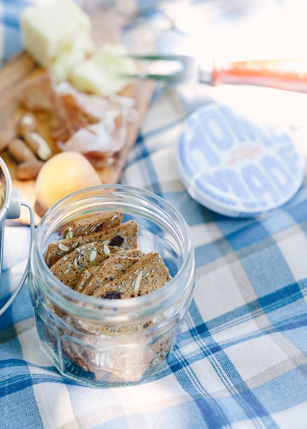 Crackers in a glass jar on a picnic blanket.