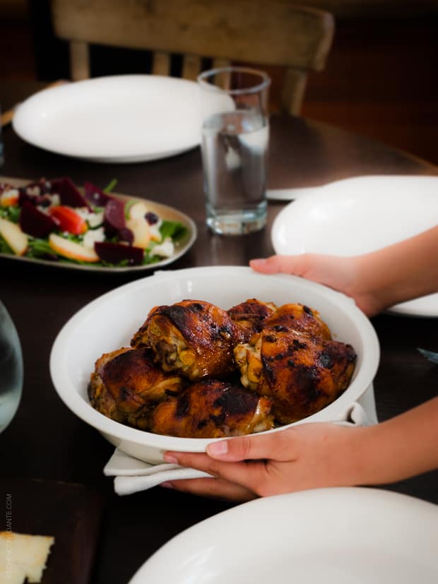 Honey Spice Marinated Grilled Chicken in a serving dish being placed onto a dinner table.