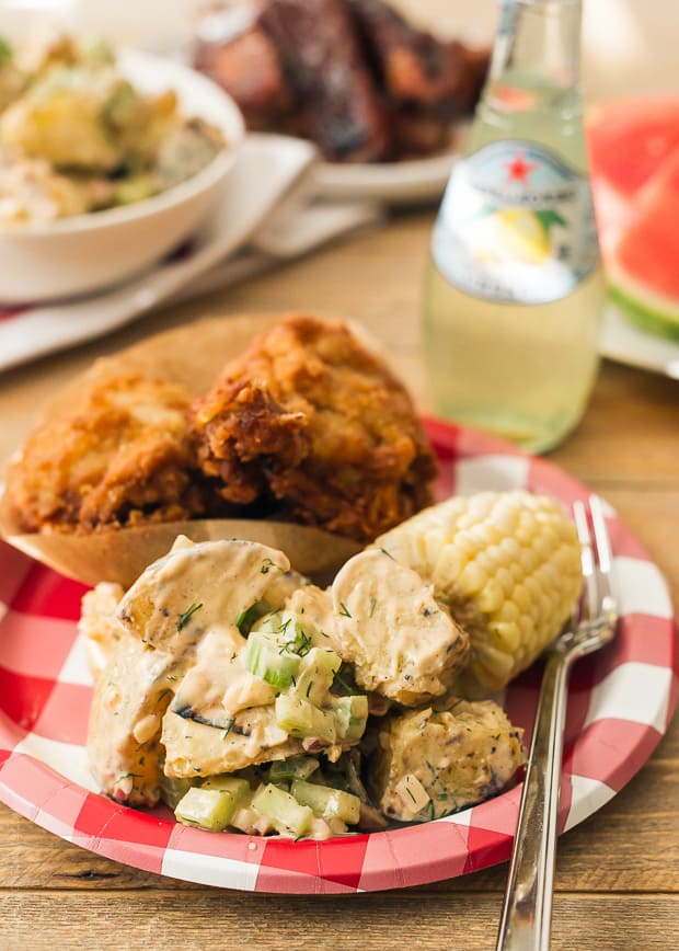 A paper plate filled with summer food off the grill. 