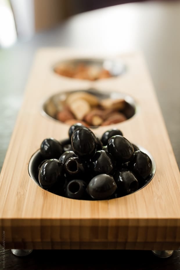 Black olives in a wooden serving dish.