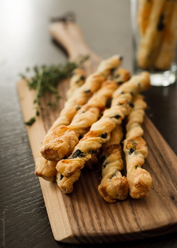 Olive Cheese Straws arranged on a wooden serving board.
