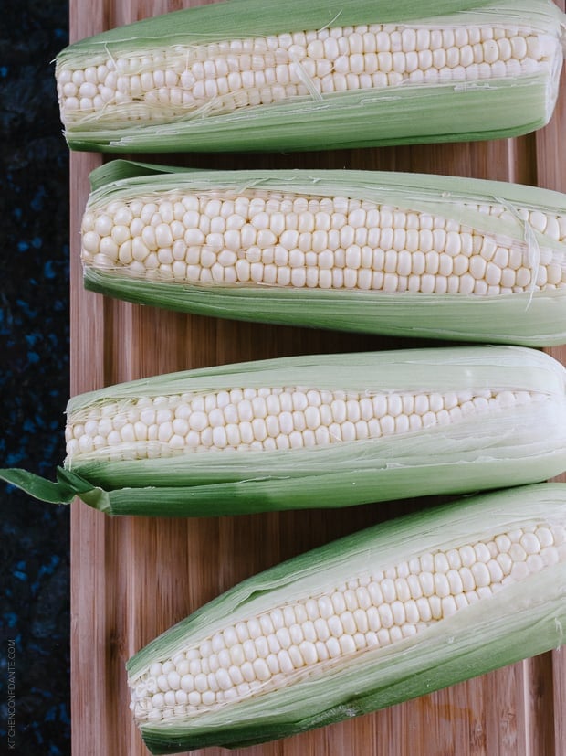 Fresh corn on the cob on a wooden surface.