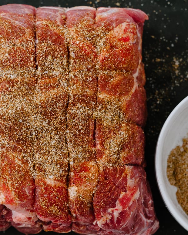 A large pork shoulder with seasonings rubbed in, ready to cook.