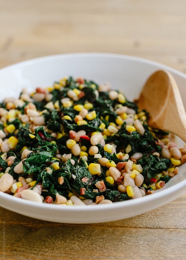 A white bowl filled with Swiss Chard with Pancetta, Corn and Cannelini Beans.