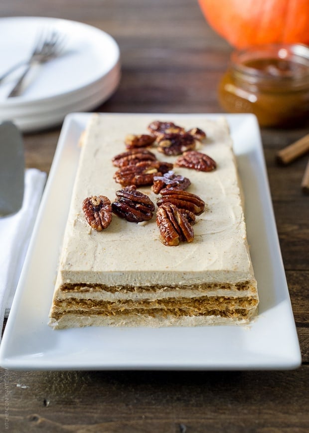 A No Bake Pumpkin Spice Kahlúa Cheesecake served a on a white rectangular platter with candied pecans on top.