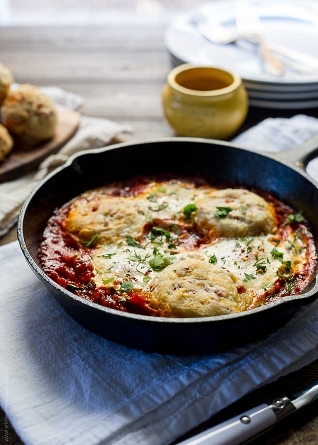 A close up view of a cast iron skillet with baked eggs and marinara sauce prepared inside.