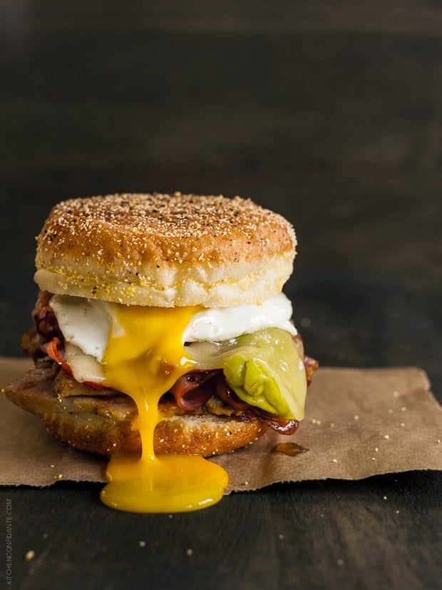 A Cubano Breakfast Sandwich made with an English Muffin and piled high with meat and a sunny side up egg.