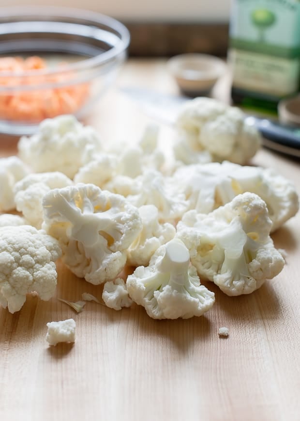 Chopped cauliflower florets on a wooden counter top.