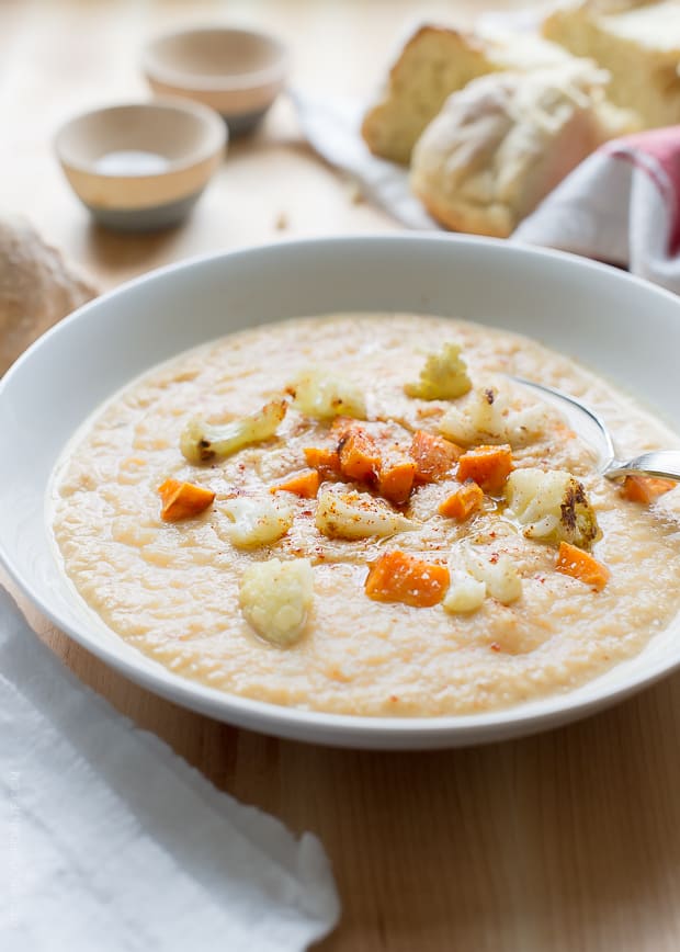 White bowl filled with Roasted Cauliflower and Sweet Potato Chowder and garnished with roasted cauliflower and sweet potatoes. 