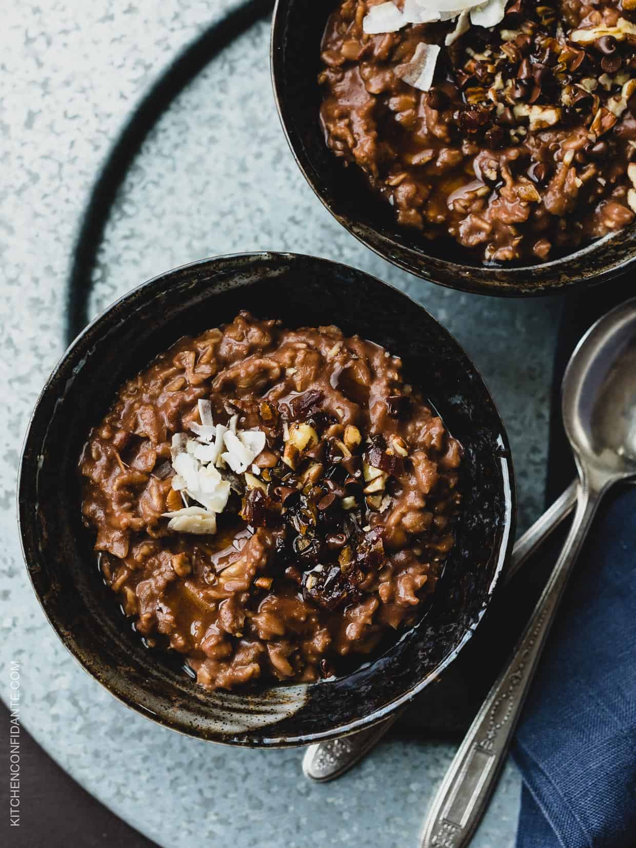 Two bowls of Chocolate Coconut Oat Porridge garnished with coconut and mini chocolate chips.