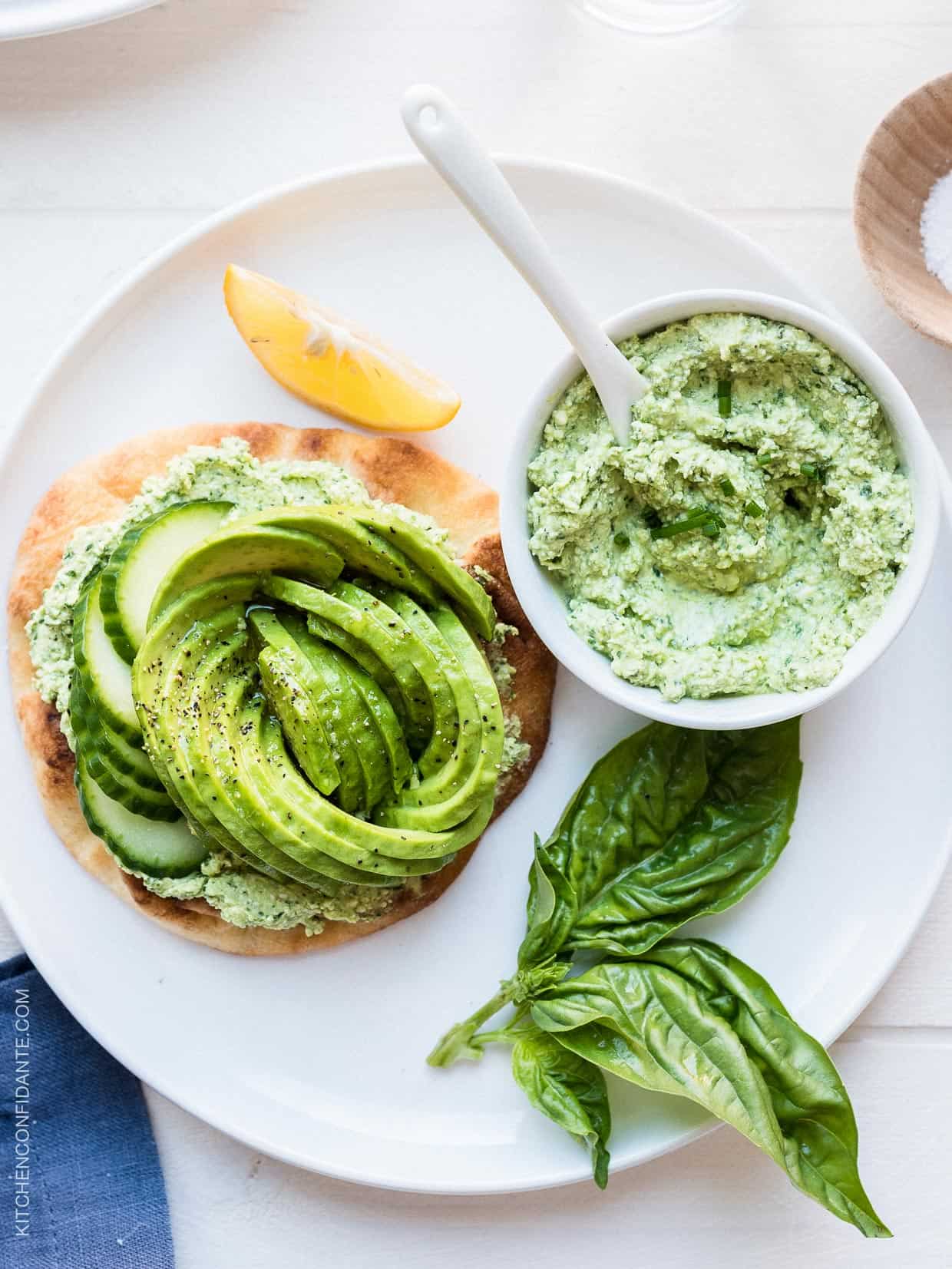 A toasted naan topped with Green Goddess feta spread and an avocado rose and garnished with basil.