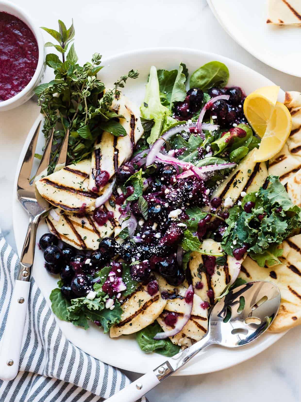 Grilled halloumi cheese served on top of a mixed green salad with a fresh blueberry dressing.