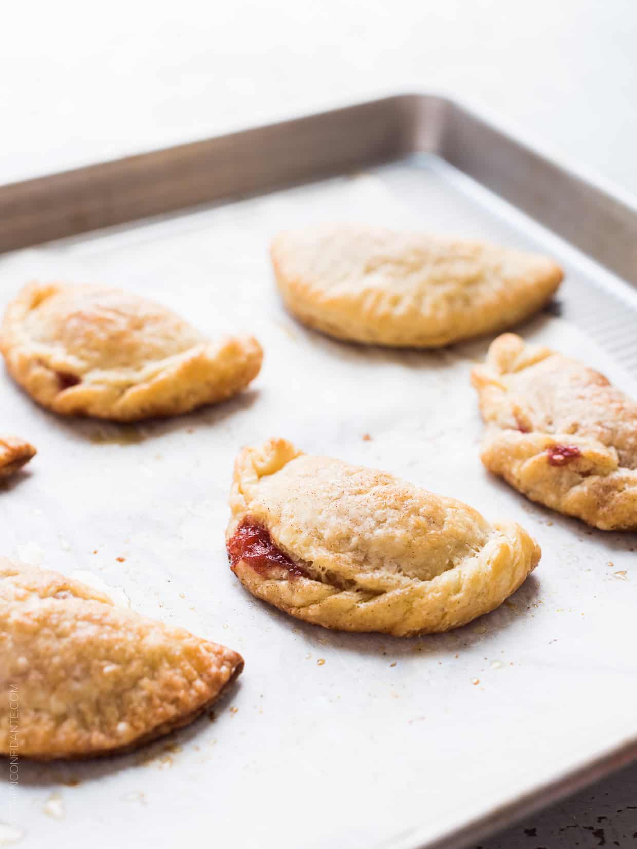 Freshly baked rhubarb empanadas on a baking sheet.