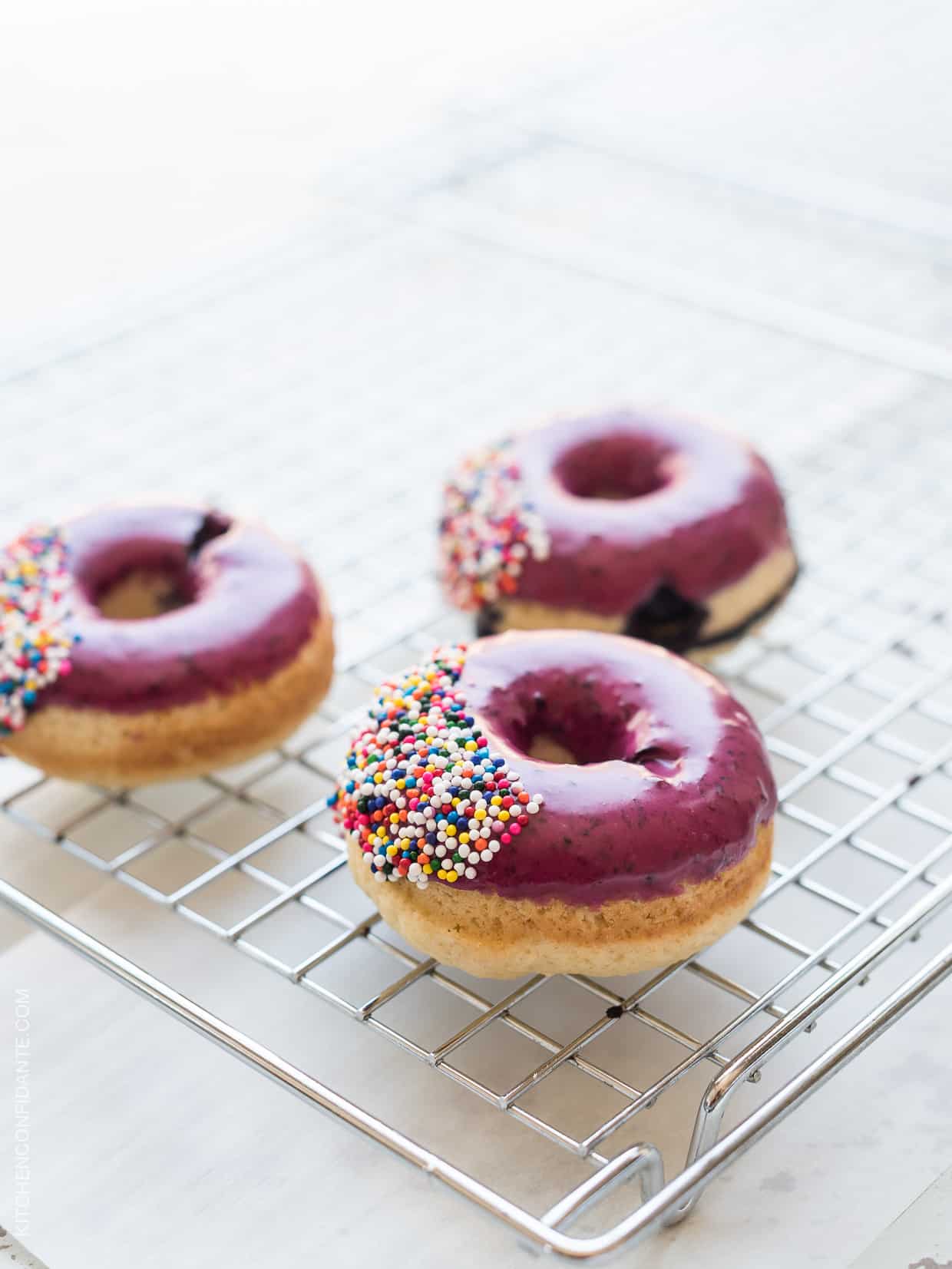 Three glazed doughnuts on a cooling rack.