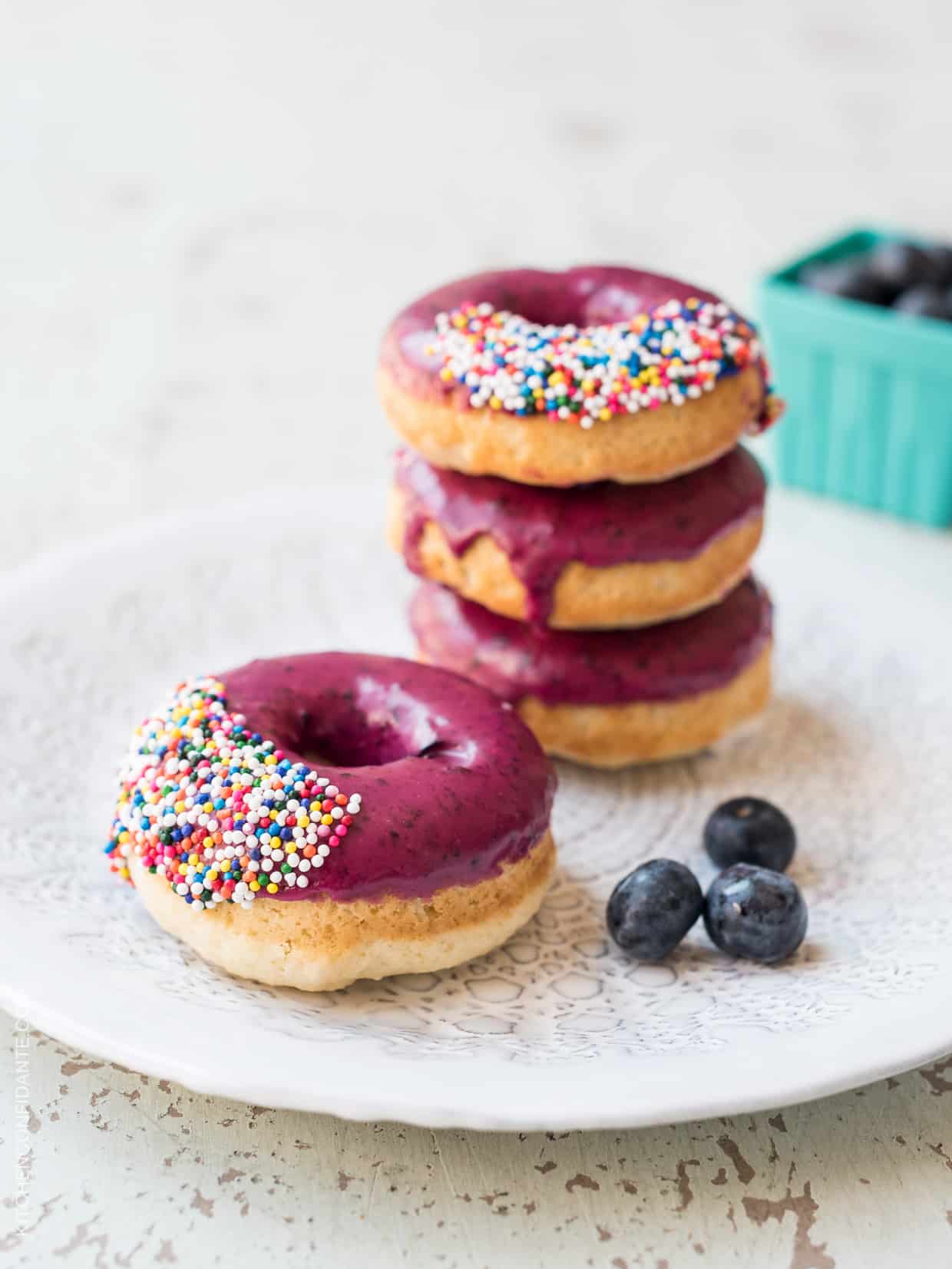 Blueberry Lemon Glazed Baked Donuts stacked on a white plate.