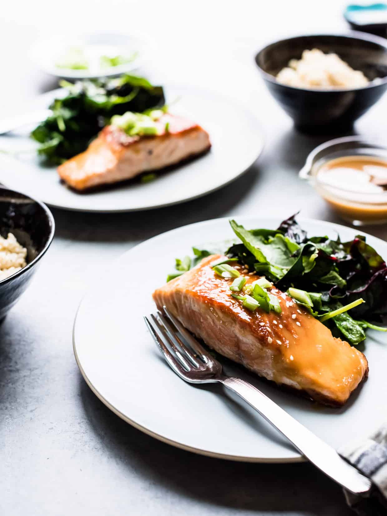 Miso Maple Glazed Salmon on a white plate served with a salad of wilted greens.