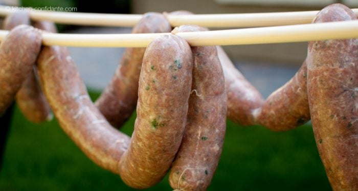 A string of homemade beer bratwurst sausages hanging on a dowel.