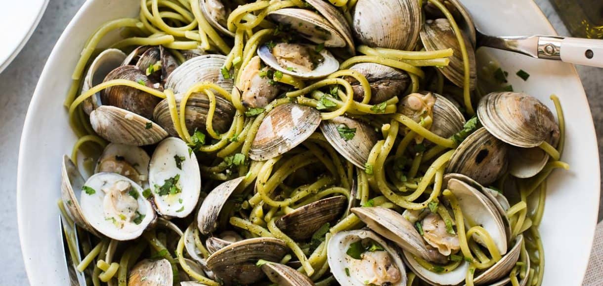 Spinach Linguine with Clams in Sake Red Chili Sauce in a white bowl.