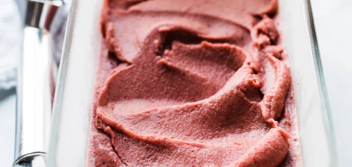 Cherry Basil Sorbet in a glass loaf pan with an ice cream scoop.