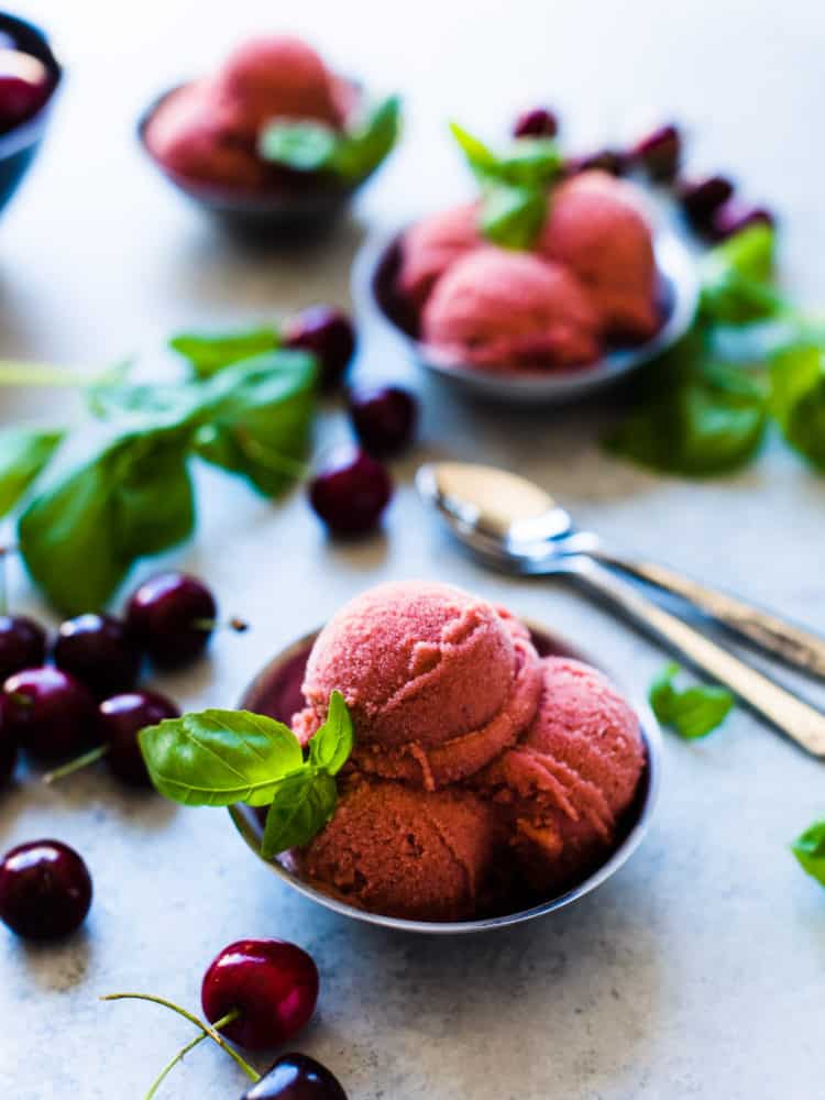 Bowls of Cherry Basil Sorbet garnished with fresh basil leaves and fresh cherries