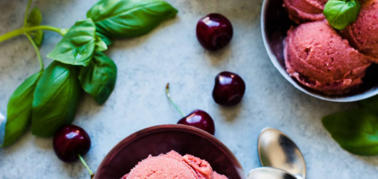 Bowls of Cherry Basil Sorbet garnished with fresh basil leaves and fresh cherries