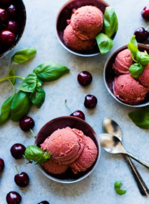 Bowls of Cherry Basil Sorbet garnished with fresh basil leaves and fresh cherries