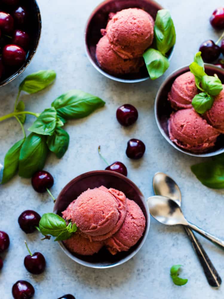 Bowls of Cherry Basil Sorbet garnished with fresh basil leaves and fresh cherries