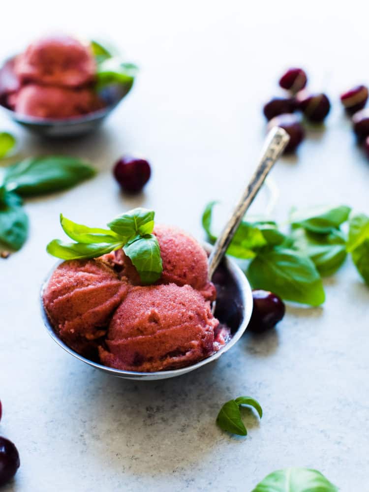 Bowls of Cherry Basil Sorbet garnished with fresh basil leaves and fresh cherries