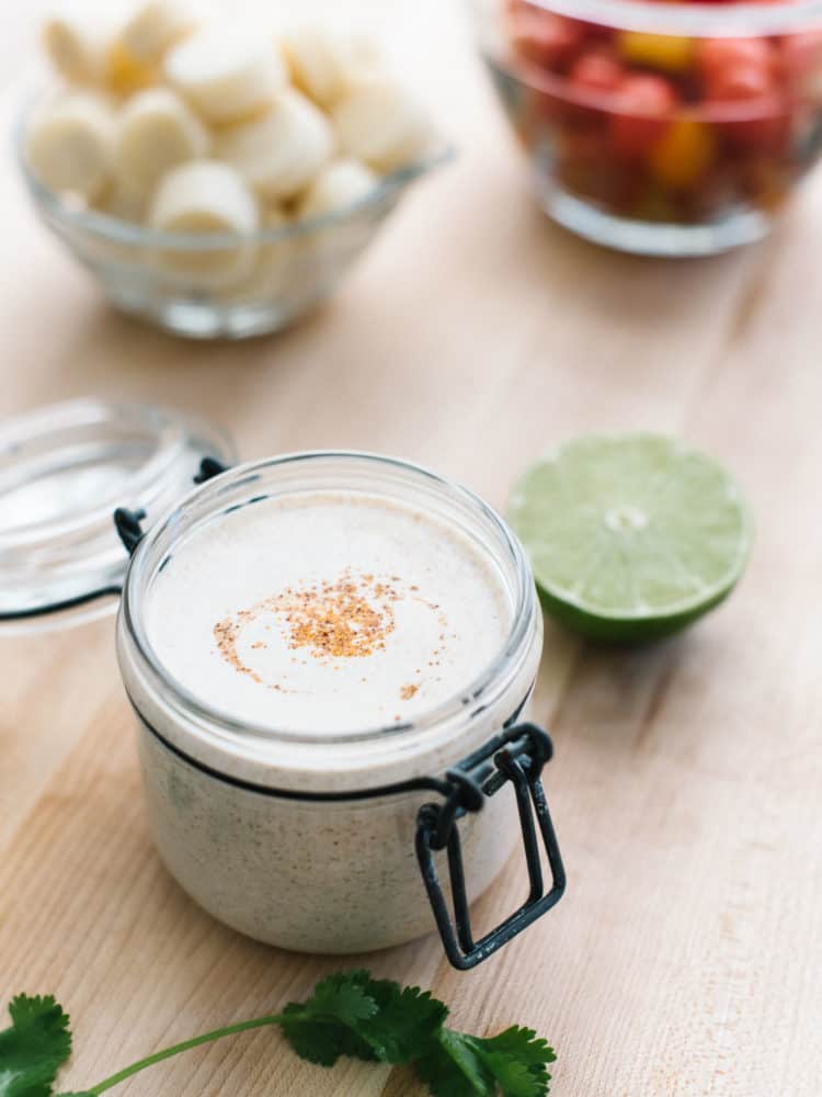 Buttermilk dressing in a small glass jar swirled with ground cumin for Southwestern Potato Salad.