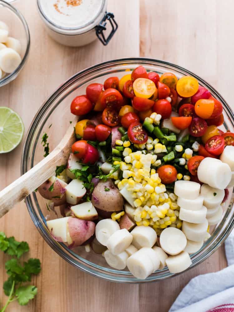 Potatoes, fresh corn, cherry tomatoes and hearts of palm in a glass bowl to make Southwestern Potato Salad