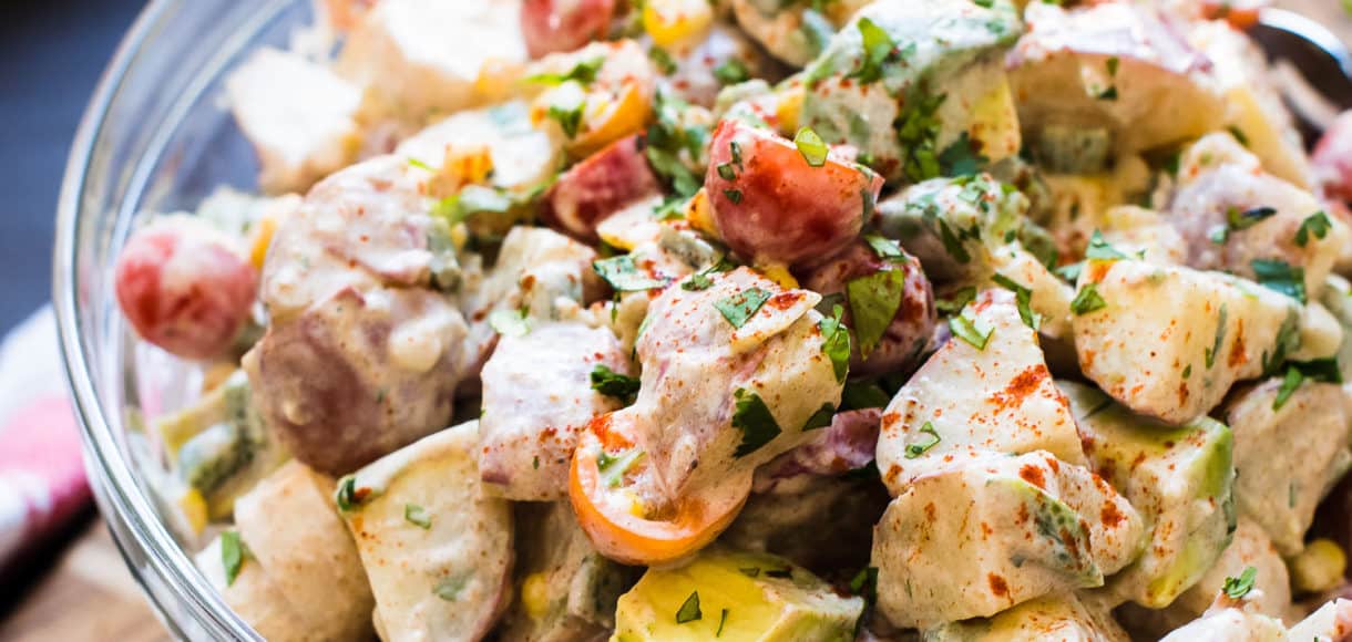 Southwestern Potato Salad in a glass bowl with potatoes, tomatoes, avocado, and corn.