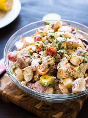 Southwestern Potato Salad in a glass bowl with potatoes, tomatoes, avocado, and corn.