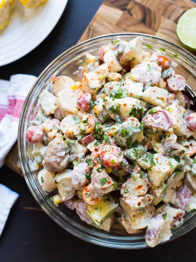 Southwestern Potato Salad in a glass bowl with potatoes, tomatoes, avocado, and corn.