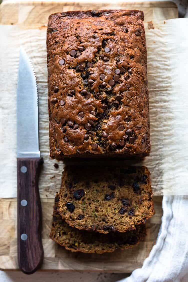 Zucchini bread with dried cranberries and chocolate chips sliced on a cutting board.