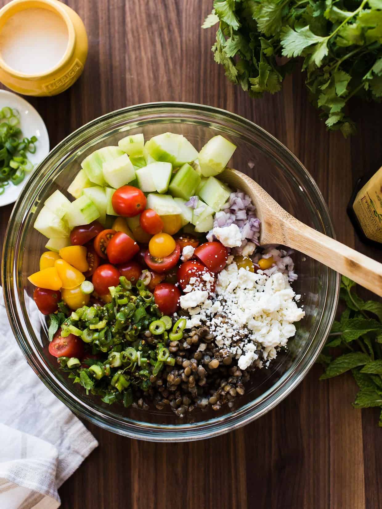 Lentils, cucumber, cherry tomatoes, feta, and red onion in a glass bowl to make Summer Lentil Salad.