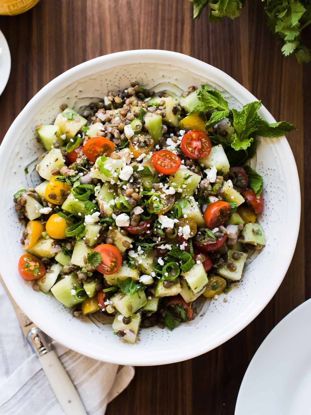 Summer Lentil Salad with lentils, cucumbers, tomatoes, and mint in a white bowl.