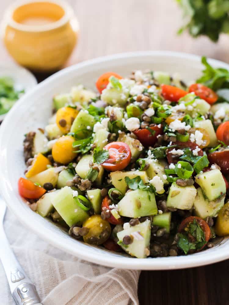 Summer Lentil Salad with lentils, cucumbers, tomatoes, and mint in a white bowl.