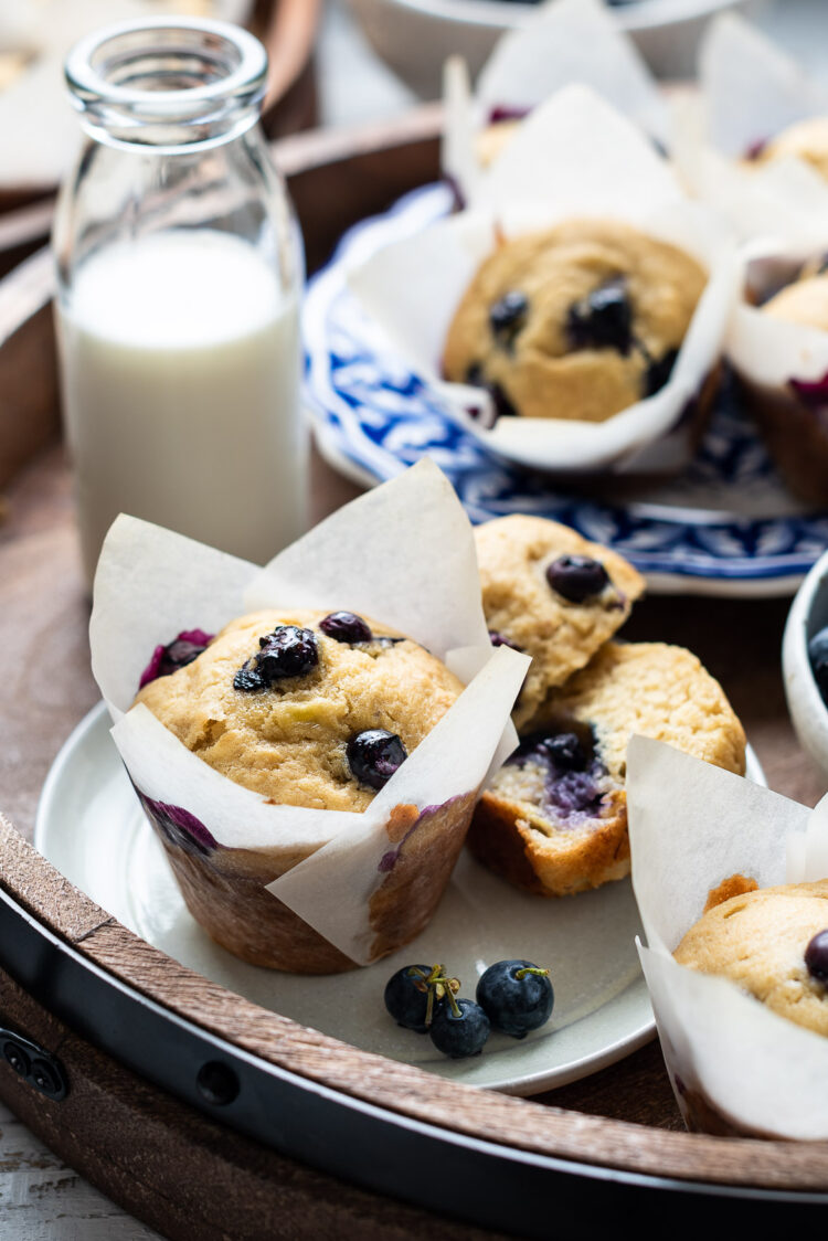 Blueberry Banana Muffins on a tray with a glass of milk.