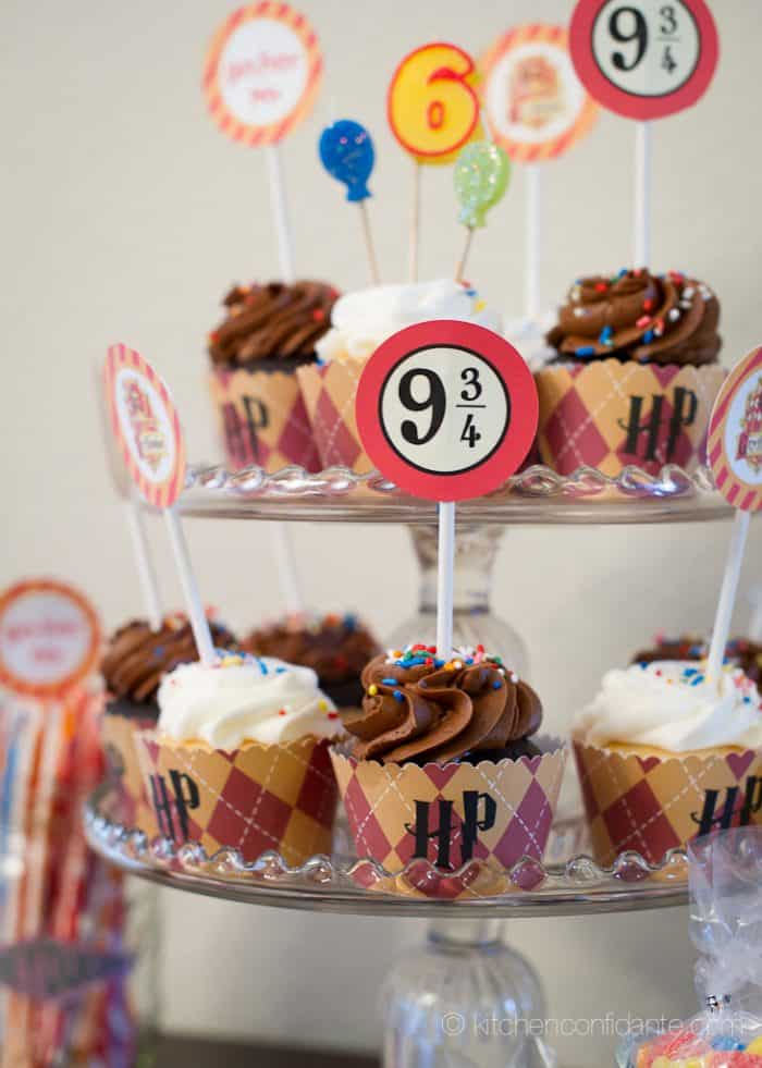 A glass tiered tower of white and chocolate cupcakes topped with Harry Potter themed signs.