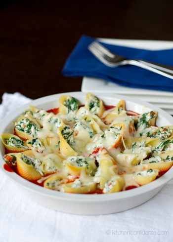 A bowl of prosciutto and spinach stuffed shells, sitting on a base of marinara sauce.