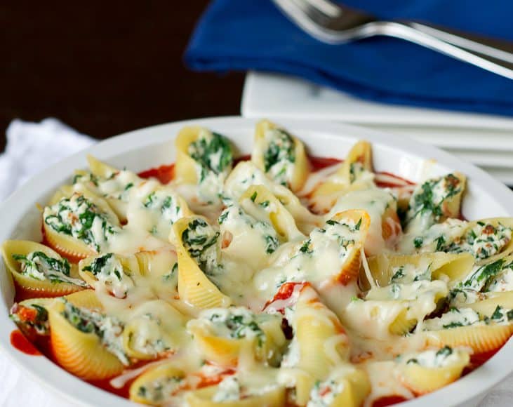 A bowl of prosciutto and spinach stuffed shells, sitting on a base of marinara sauce.