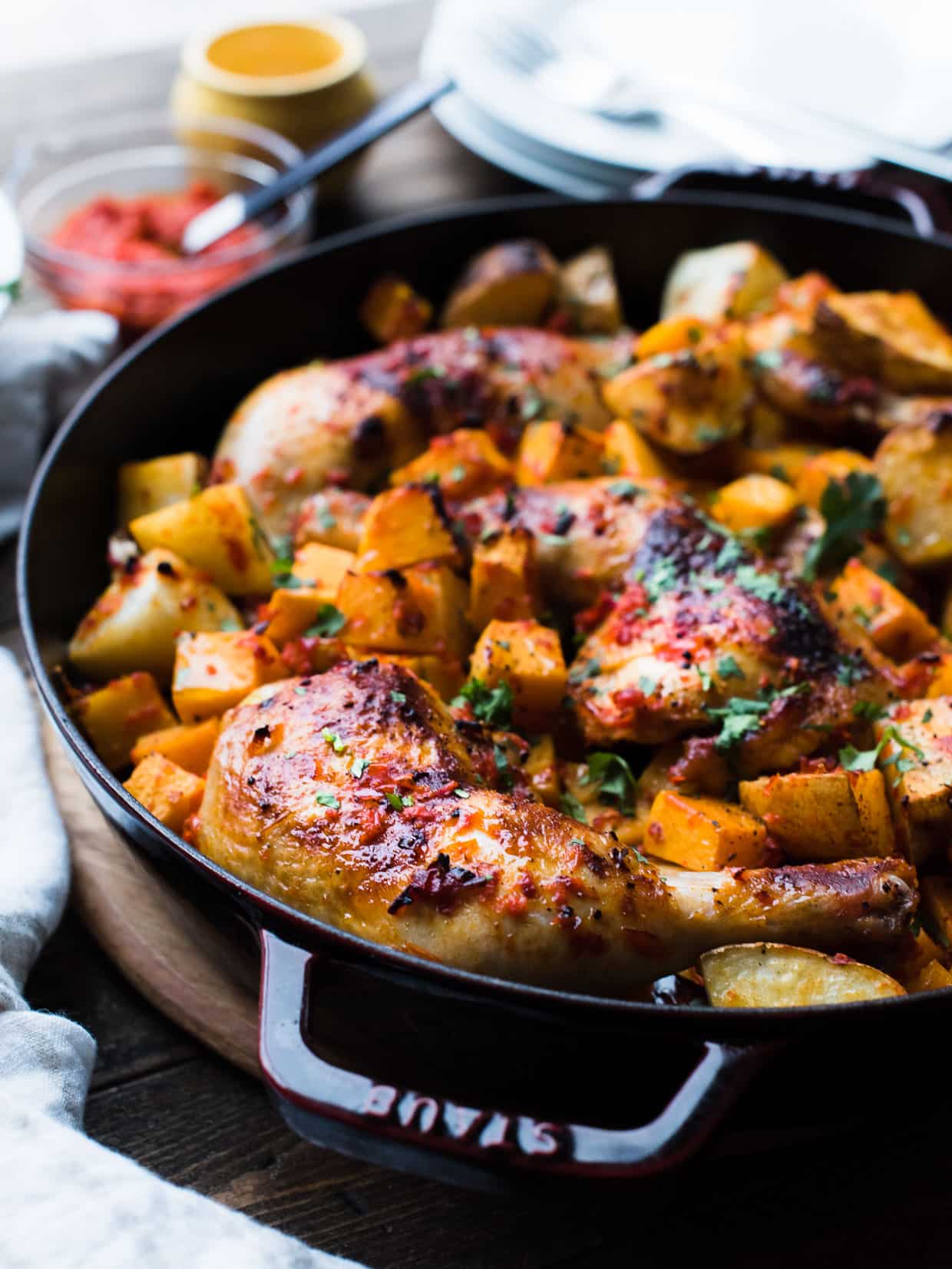 Close up view of Harissa-style Roast Chicken with Butternut Squash and Potatoes served in a Dutch oven.