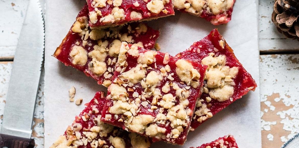 Cranberry Curd and Hazelnut Shortbread Bars on a white marble board lined with parchment paper.